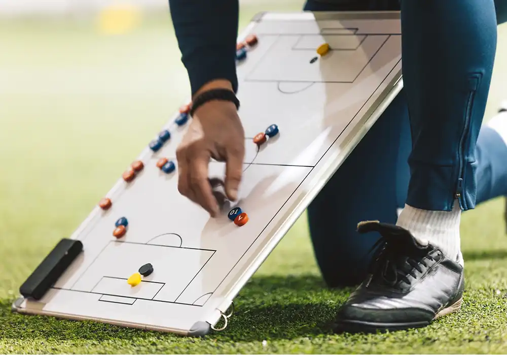 Der Coach für eure Förderungen mit einem Brett das ein Fußballfeld anzeigt